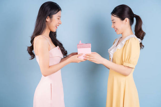 Two young females, one giving, the other accepting a gift.