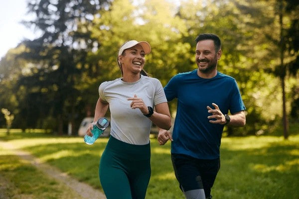 Happy Healthy Young Couple - running through a park