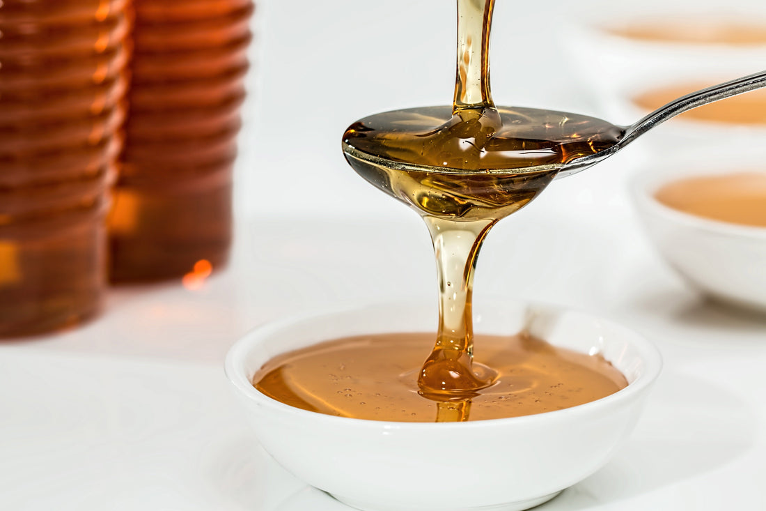 Pouring Pure New Zealand Manuka Honey onto a spoon and into a bowl.