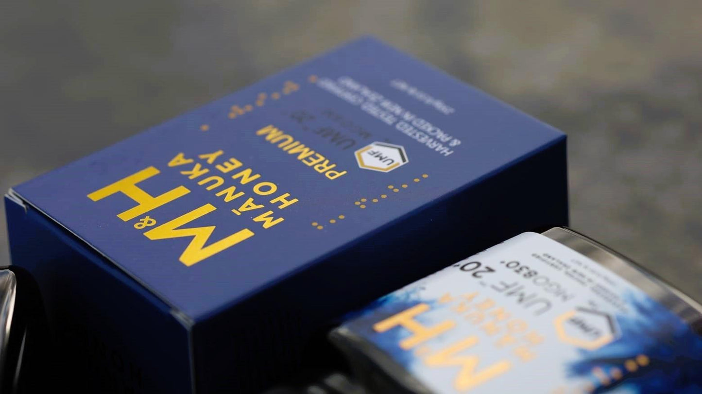 Blue M&H manuka honey box and Jar with yellow text on a blurred background