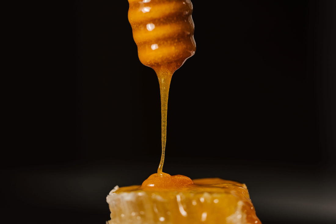 Manuka Honey, dripping down from a stirring spoon onto some honeycomb